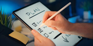 Pessoa usando tablet com caneta digital para planejar tarefas em checklist, representando organização, planejamento e produtividade digital.