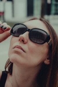 Chic portrait of a woman wearing trendy sunglasses reflecting numbers, captured in a modern setting.
