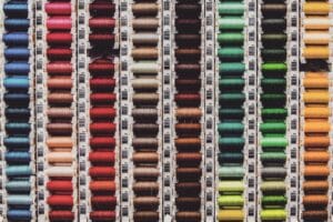 A vibrant array of colored thread spools neatly organized in rows, perfect for sewing enthusiasts.