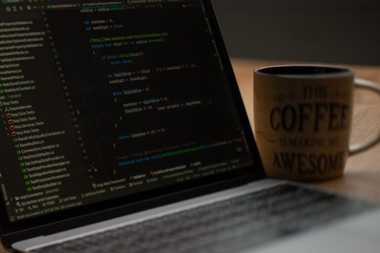 Close-up of a laptop screen with code and a coffee mug, perfect for tech abstract themes.