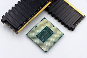 A CPU and RAM sticks displayed on a white surface, showcasing computer hardware components.