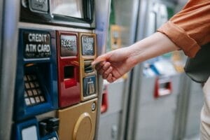Close-up of a person using a metro card machine for public transport payment indoors.