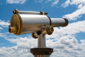 A close-up of a coin-operated telescope set against a beautiful cloudy sky, ideal for travel imagery.