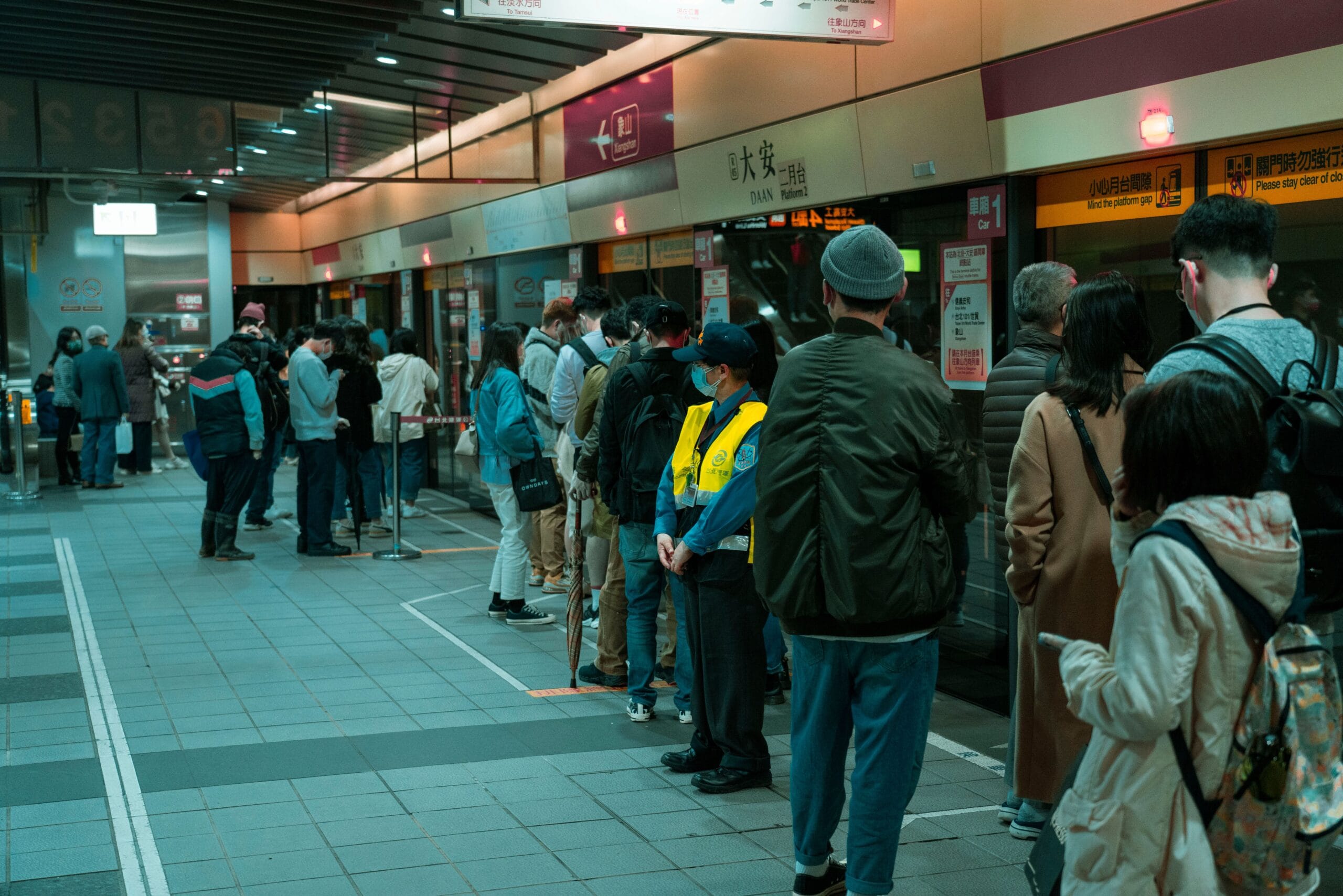 Commuters line up at a subway station platform, showcasing public transportation dynamics.