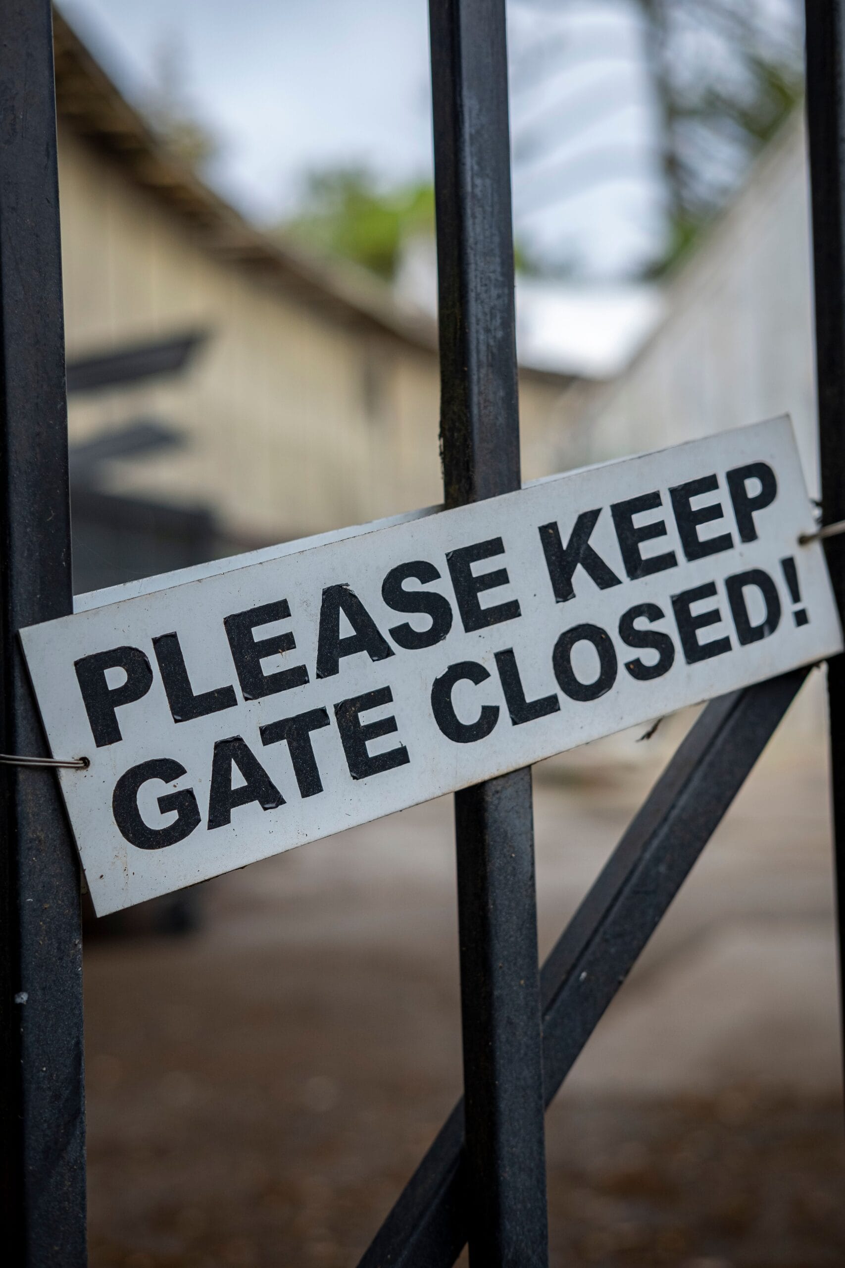 Close-up of a metal gate featuring a 'Please Keep Gate Closed' sign, outdoors.