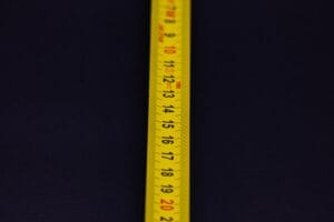 Detailed shot of a yellow measuring tape with numbers on a dark background.