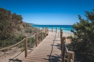 Picturesque wooden boardwalk leading to a serene beach under clear blue skies.