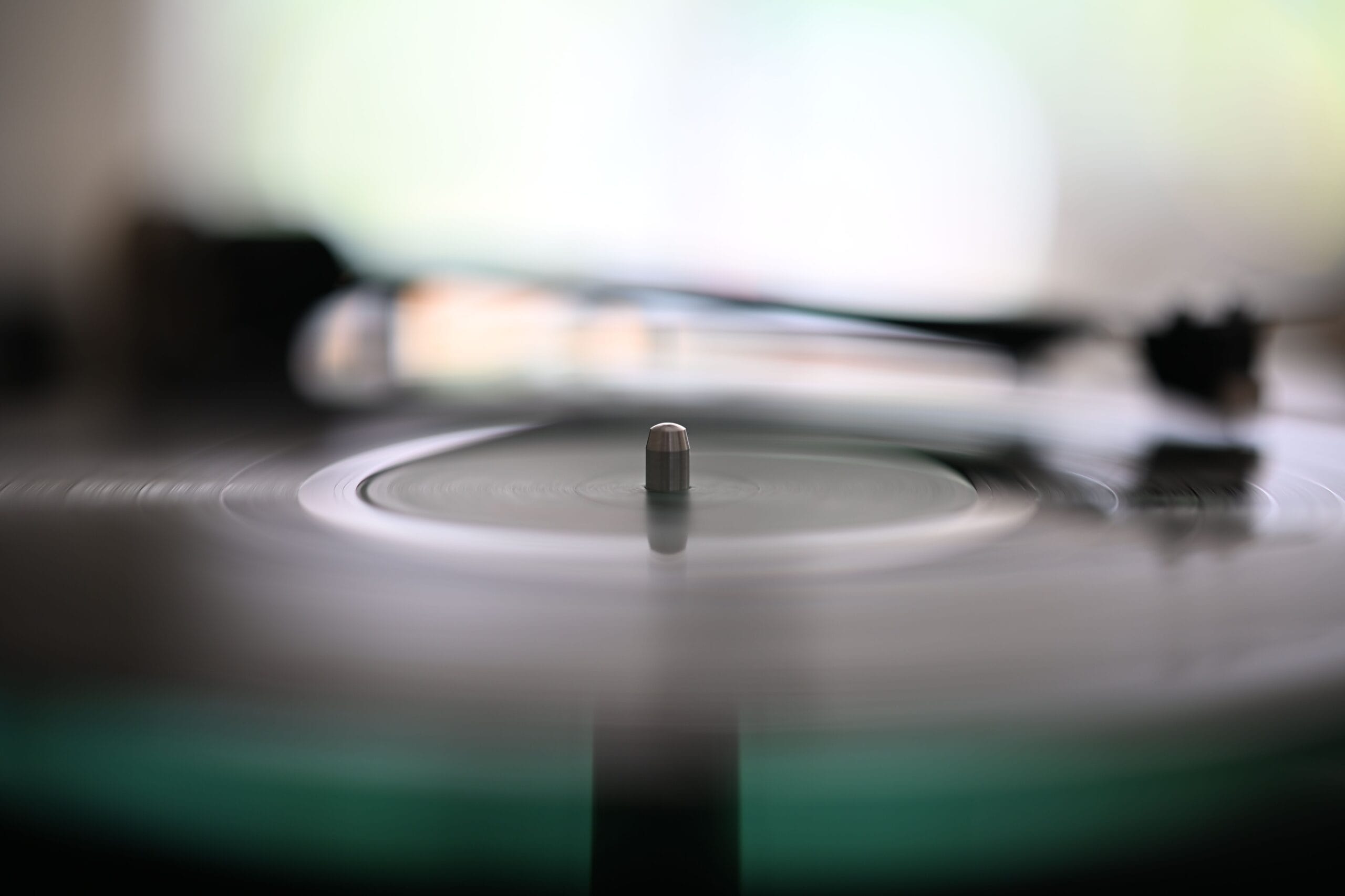 Blurry spinning vinyl record with needle on turntable, capturing the essence of analog music.