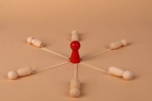 Red leader figure connected to wooden figures, emphasizing leadership and teamwork.