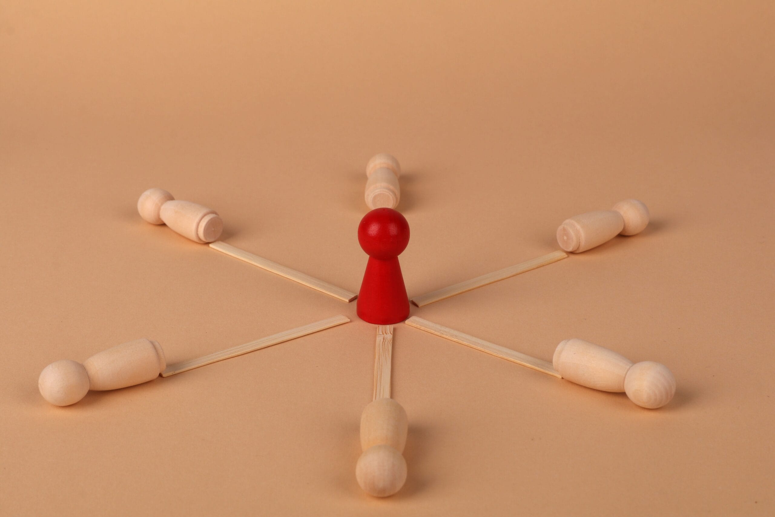 Red leader figure connected to wooden figures, emphasizing leadership and teamwork.