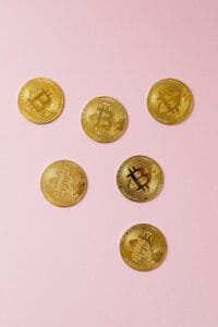 Flat lay of gold bitcoin coins on a pink surface, symbolizing cryptocurrency and modern investment.