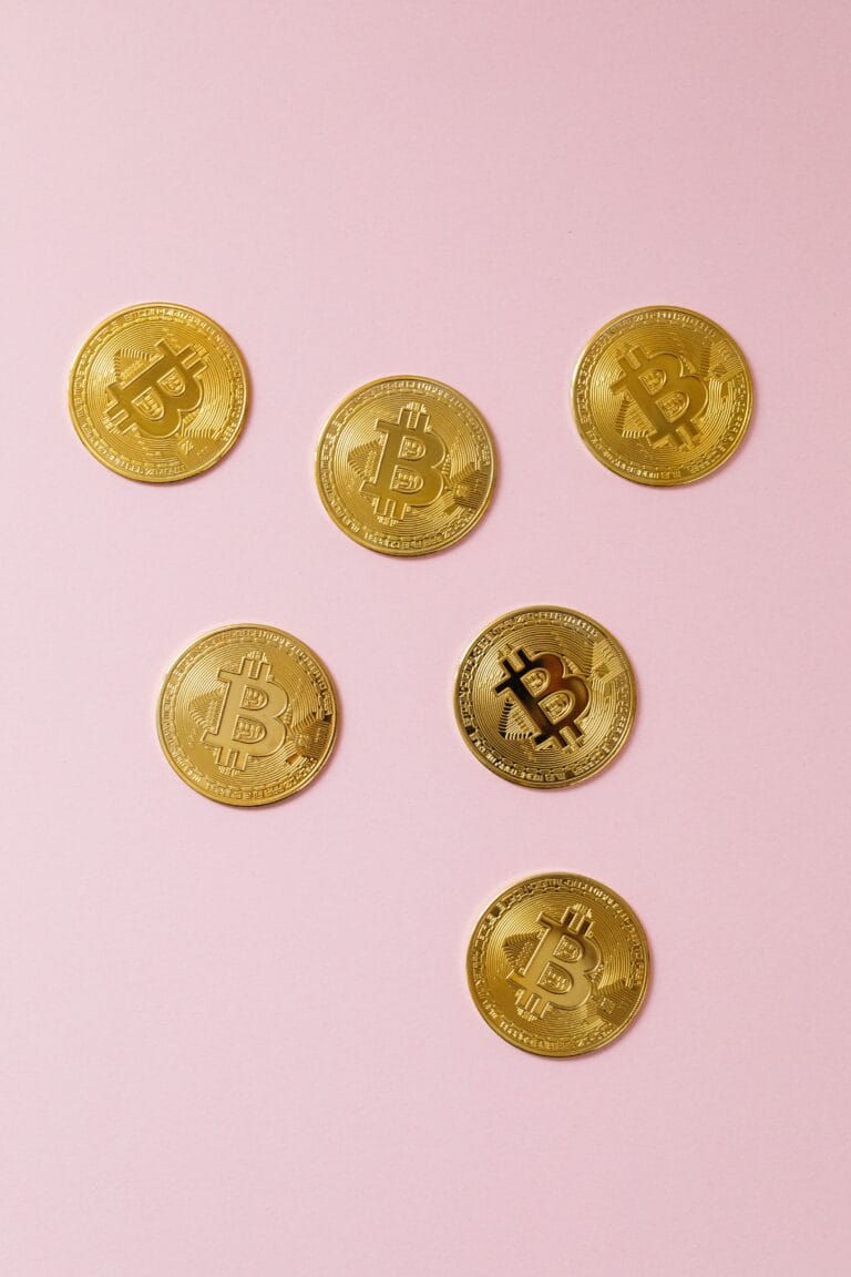 Flat lay of gold bitcoin coins on a pink surface, symbolizing cryptocurrency and modern investment.