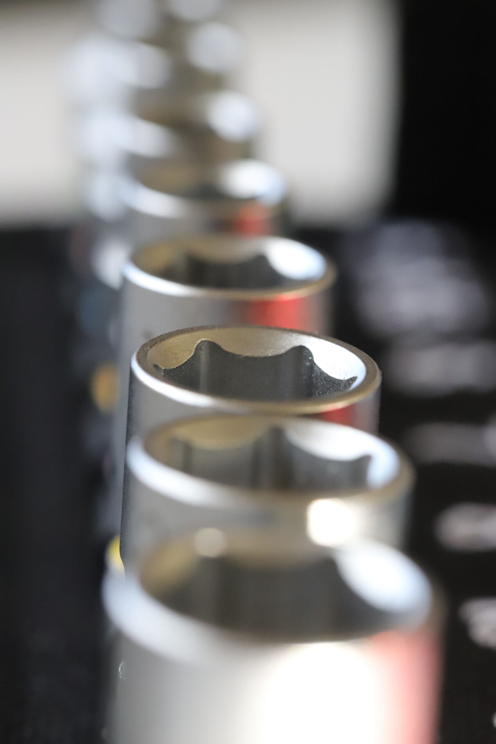 A vertical macro shot showcasing metallic socket wrenches in a shallow focus arrangement.