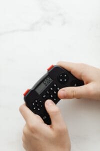 Close-up of hands using a compact black calculator on a white marble surface, displaying numbers.